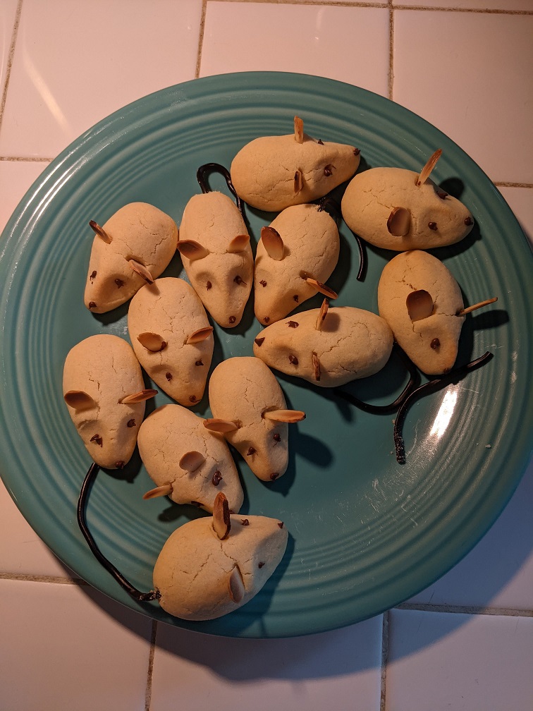 Several cookies designed to look like mice sitting on a blue plate.